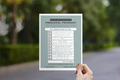 Person holding a checklist for an exciting preschool program against a blurred outdoor background