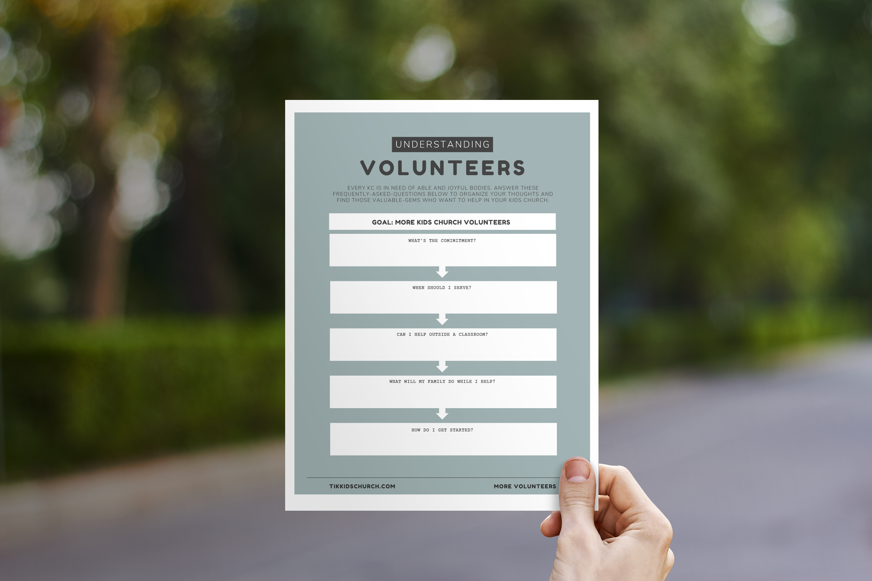 Hand holding a flyer titled 'Understanding Volunteers' with a blurred outdoor background
